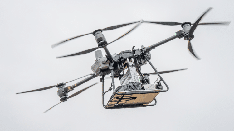 A large industrial drone in flight carrying a compact 5G base station payload, tested at Oulu Zone in Oulu, Finland, as part of a joint University of Oulu and University of Tokyo emergency communications research project.