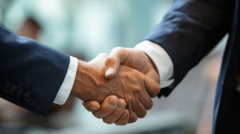 Two businessmen in suits shaking hands, symbolizing the partnership between 6G Flagship and Bharat 6G Alliance.