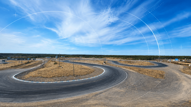 Aerial view of the OuluZone test track under a blue sky, with graphic arcs representing radio signals over the horizon.