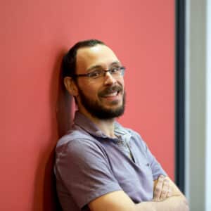 Docent Pedro Nardelli leaning against a red wall.