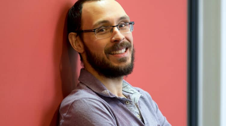 Docent Pedro Nardelli leaning against a red wall.