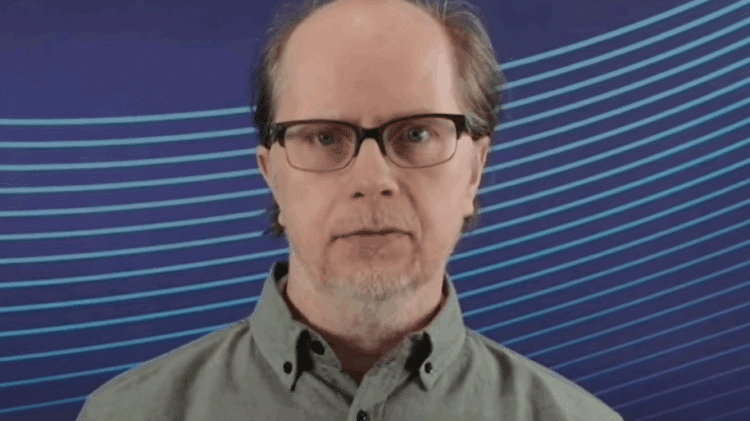 Adjunct Professor Sami Myllymäki standing in front of a blue striped background