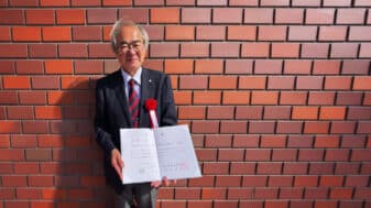 Professor Tadashi Matsumoto holding the IEICE Education Award certificate in Japan