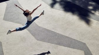 Young woman leaping across a sunny yard